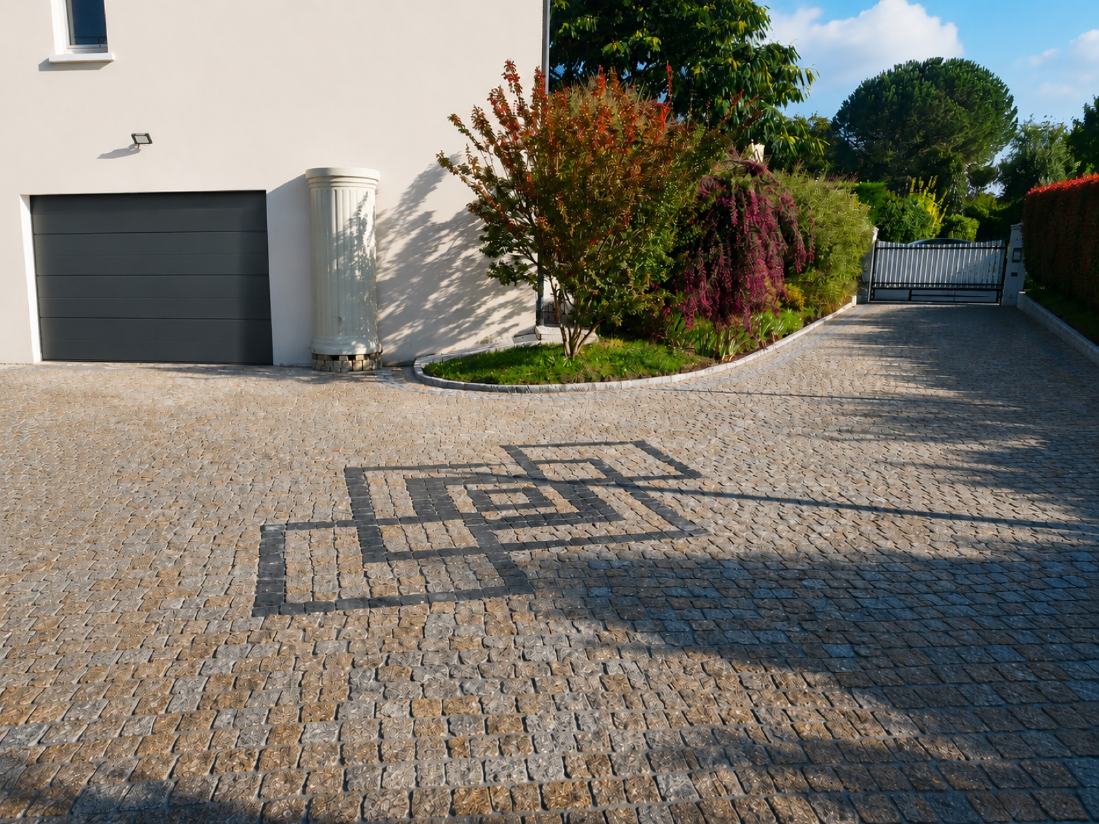 Cour et allée en pavés granit avec motif décoratif intégré, devant garage et portail, lumière de fin de journée