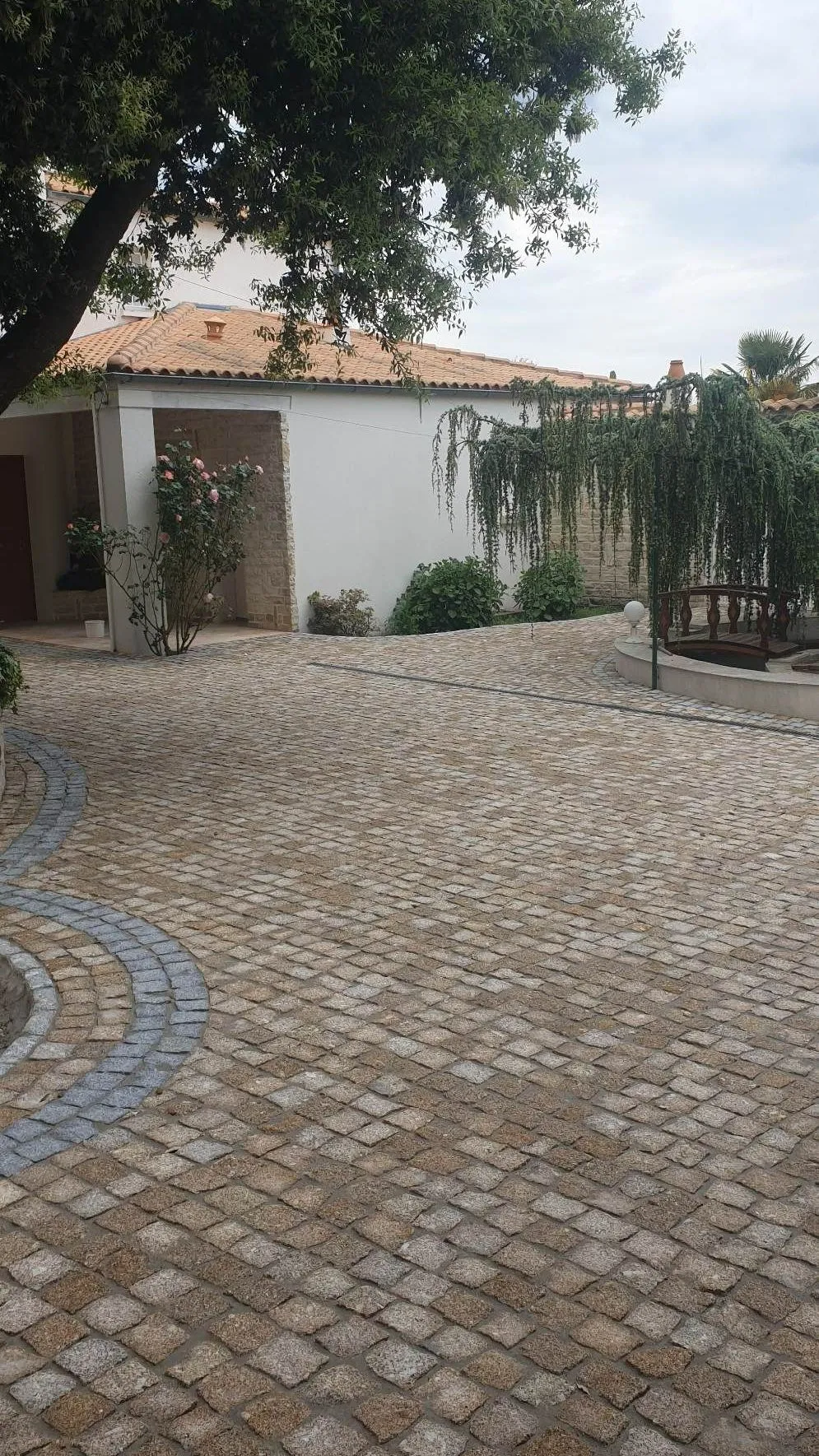 Cour en pavé doré traversée d'une bande courbe en granit gris