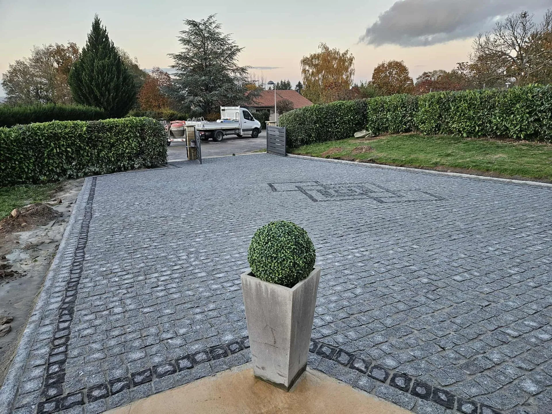 Cour en pavés granit gris au crépuscule devant une propriété