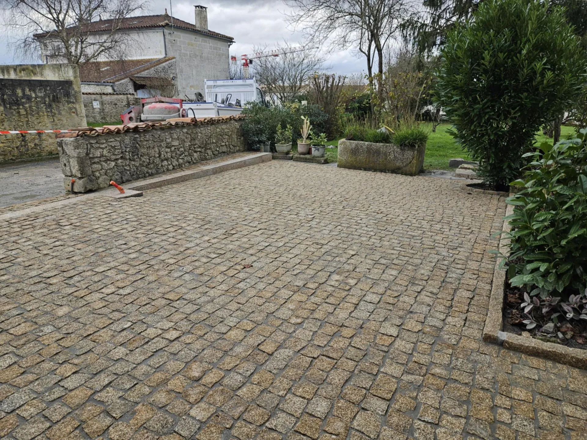 Cour en pavé granit doré bordée d'un mur en pierre ancienne