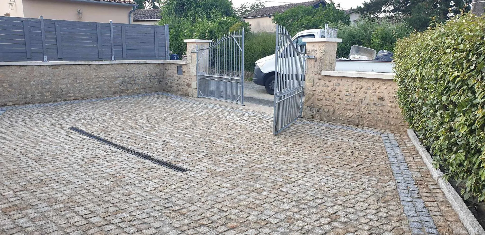 Entrée de propriété en pavé granit doré avec caniveau de drainage intégré